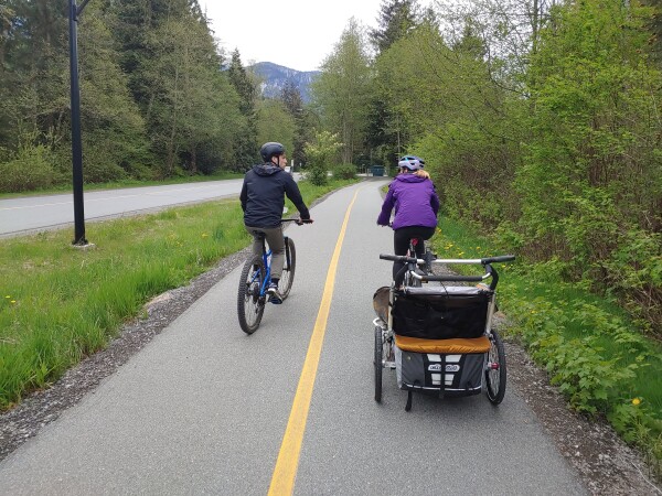family cycling  along an off-street multi-use pathway pulling a children's bicycle trailer