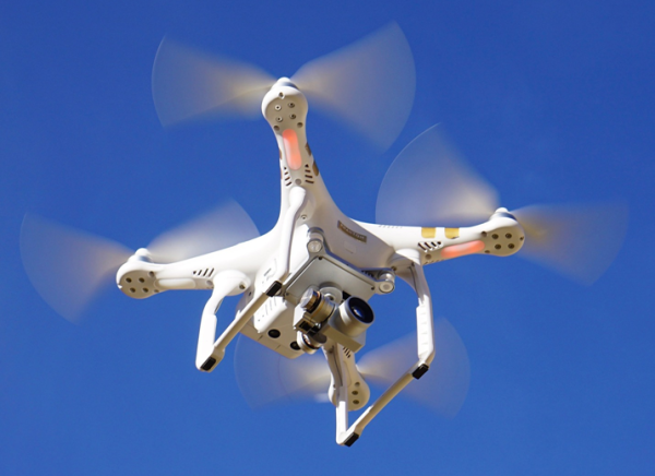 White drone in flight against blue sky.